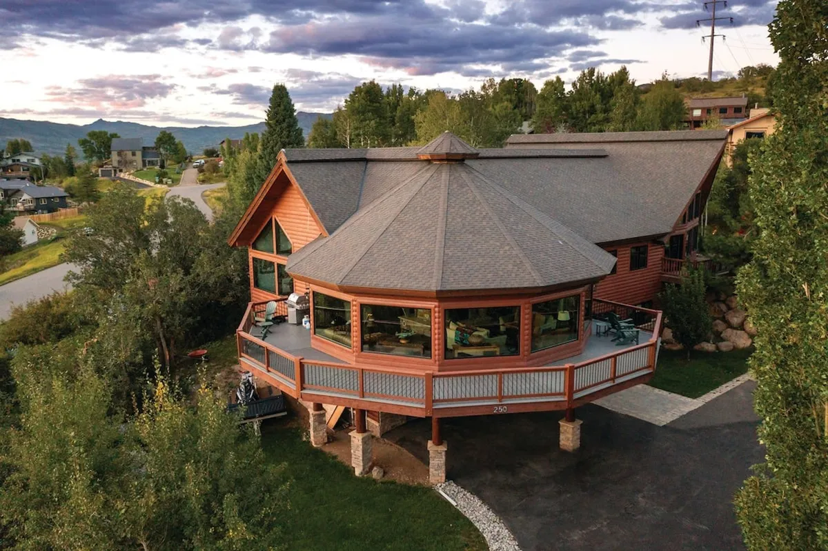 The unique octagonal architecture of the lodge is showcased here, with large windows and natural surroundings. The image radiates a sense of welcome and tranquility, perfect for group gatherings or sunset viewing.