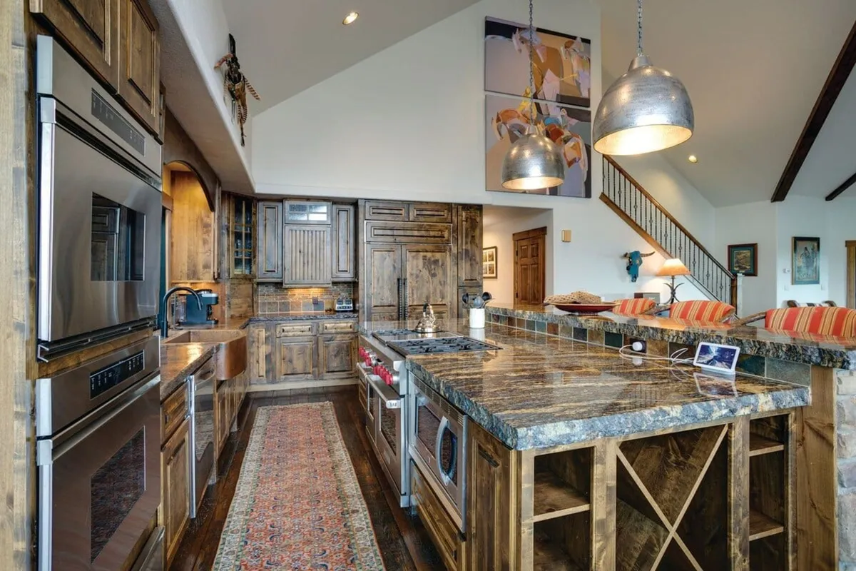 A kitchen featuring a granite countertop, wooden cabinetry, a functional island, and visible modern appliances. The layout is practical and inviting, perfect for cooking and socializing with family or friends.
